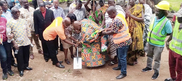 Oyeeman Nana Osim Kwatia II, Chief of Amanokrom and Gyasehene of Akuapem, assisted by Ayimah Edomgbole, Project Manager of Ghana Gas, and Veronica Dery, Headmistress of the Akropong School for the Blind, performing the sod-cutting ceremony while other officials look on